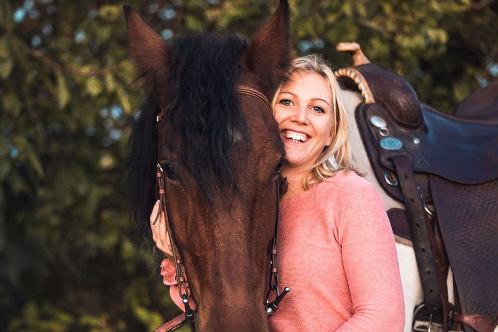 Lachende Frau mit gesatteltem Pferd